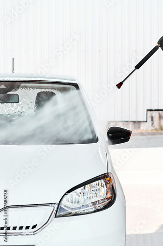 Obraz na plátně A white car washing with pressurized water at self wash service outdoors at sunny day
