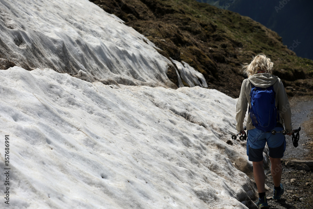 Wanderin beim überqueren eines Schneefeldes in den Bergen
