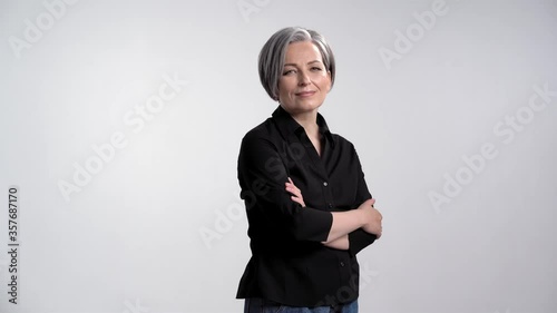 Sensual kind adult gray haired woman with arms crossed showing facial expressions posing for photographer in studio on a white background in casual clothes black shirt and jeans. Prores 422.