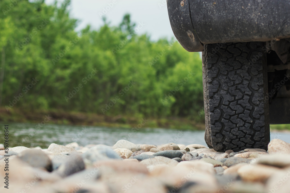 An old tourist car is standing on the bank of a river in Siberia. SUV wheel close-up. Traveling in Russia in the summer. An old tourist car is standing on the bank of a river in Siberia. SUV wheel close-up. Traveling in Russia in the summer.