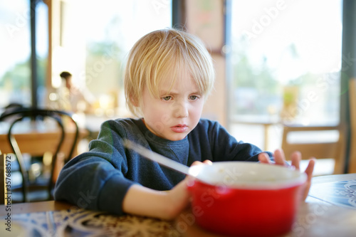 Little boy sitting the table in cafe or restaurant and doesn t want to eat. Healthy food. Kids diet. Poor appetite.