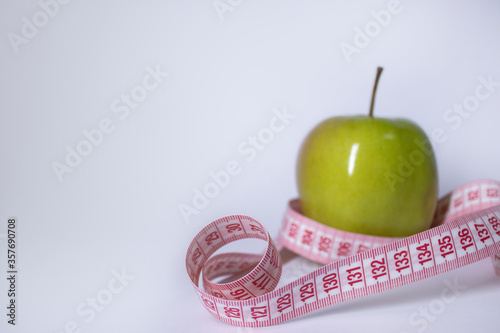 Red measuring tape over green apple. Diet and Healthy life, loss weight concept. Top view. Copy space. Isolated. White background. High quality photo