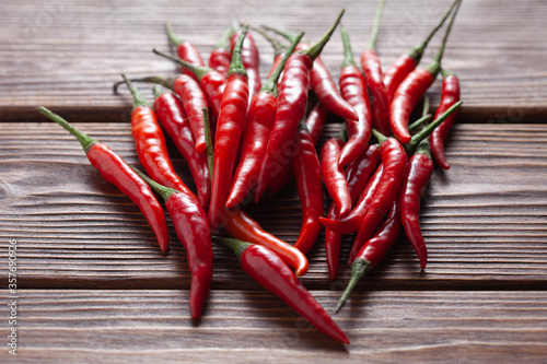 hot red chilli pepper in pods on wooden table