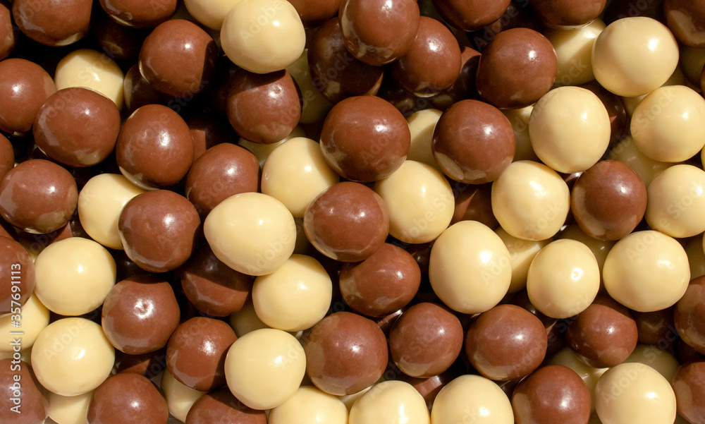 Background made of chocolate hazelnuts covered with milk chocolate and white chocolate. Choco hazelnuts dragee backdrop Background made of chocolate hazelnuts covered with milk chocolate and white chocolate. Choco hazelnuts dragee backdrop