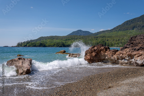 Beautiful pristine tropical looking Bonanza beach with turquoise waters crashing into the rocks creating a unique spray on a sunny blue sky day in Haida Gwaii, British Columbia, Canada.