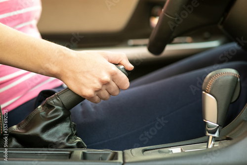 Close up of female driver hand holding hand brake in a car.