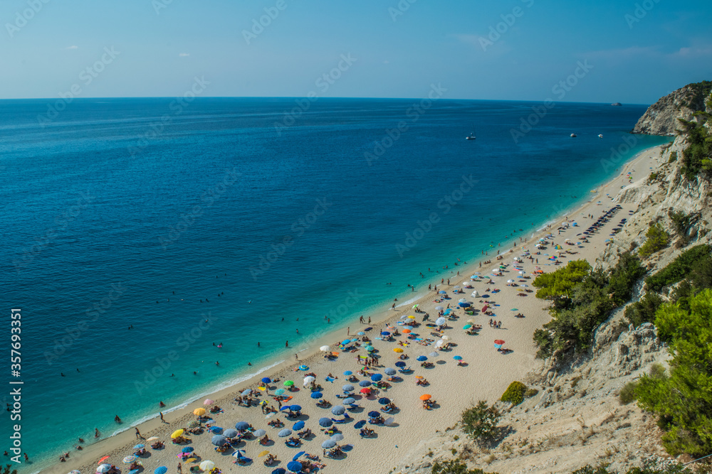 Photo of Egremni beach with turquoise water and full of people sunbathing at Lefkada island, Greece