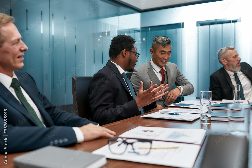Multicultural business people in formal wear discussing new project while having a meeting in the modern office Multicultural business people in formal wear discussing new project while having a meeting in the modern office