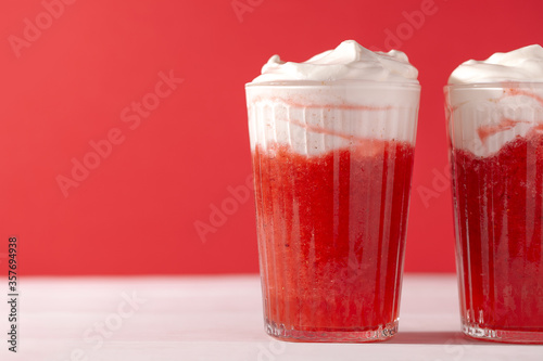 Foto Strawberry smoothie shakes in glass with whipping cream on red background with copy space