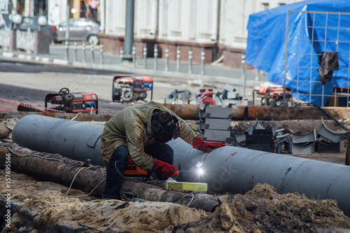 Repairing of city water supply or sewer pipeline. Worker is welding pipe