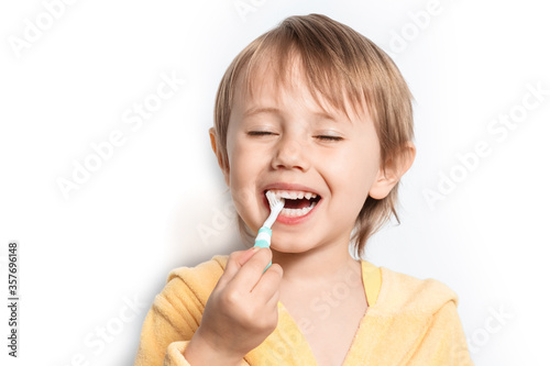 Cute happy adorable little girl dressed in yellow bathrobe brushing her teeth.