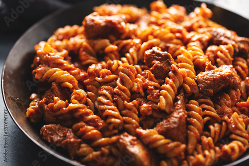 Pasta penne with sauce and meat served on pan