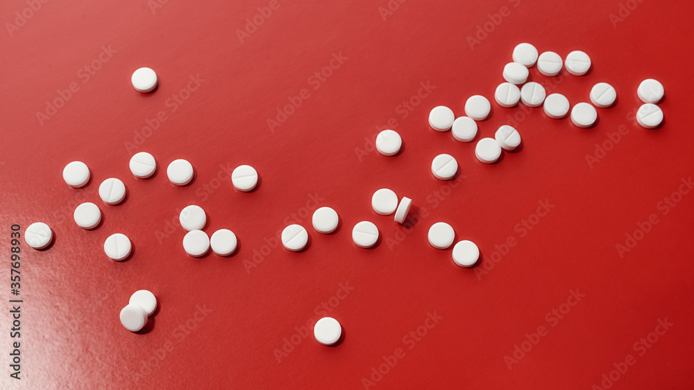 White pills scattered, lying randomly over red background. Heart and cardiovascular disease, health and treatment concept. White pills scattered, lying randomly over red background. Heart and cardiovascular disease, health and treatment concept.