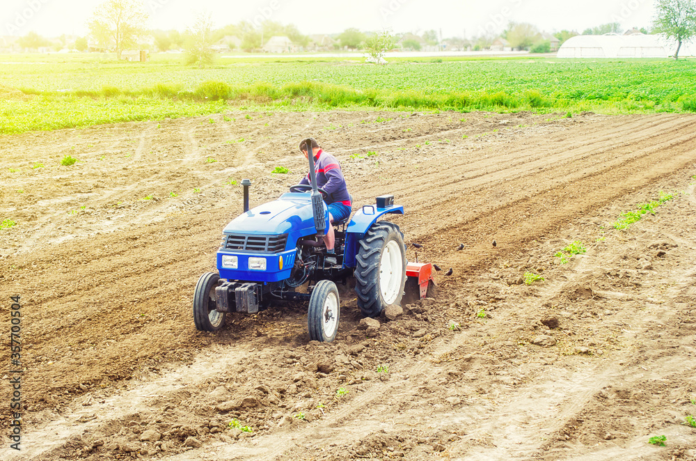 Obraz premium A farmer on a tractor cultivates a farm field. Soil milling, crumbling and mixing. Loosening surface, cultivating land for further planting. Agroindustry, farming. Preparatory work for a new planting.