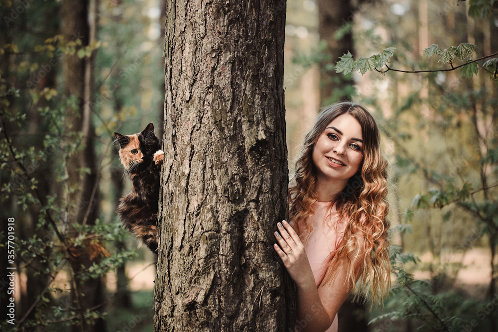 Girl and cat. Spring or summer warm weather concept. Bokeh background. Ginger kitten with two face color mask Girl and cat. Spring or summer warm weather concept. Bokeh background. Ginger kitten with two face color mask