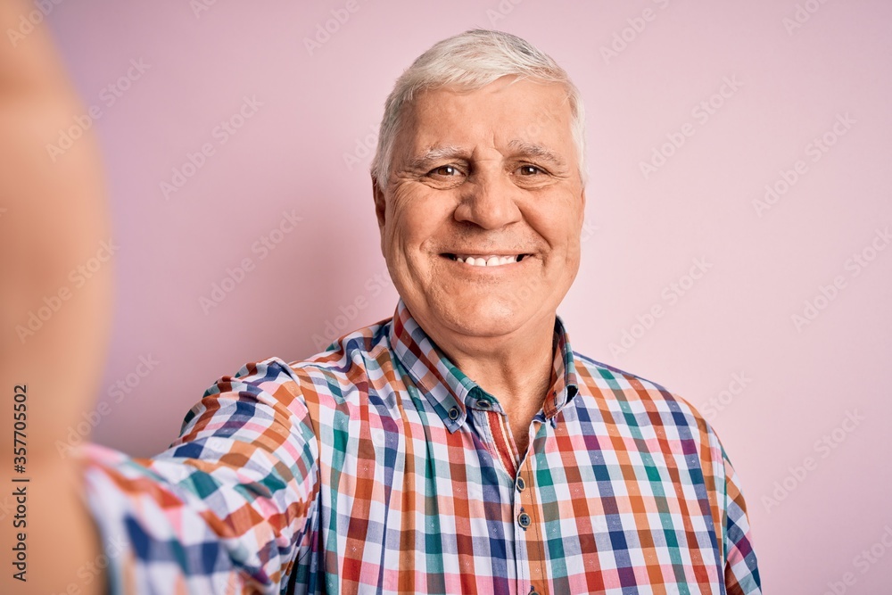Senior handsome hoary man wearing casual shirt making selfie by the camera with a happy face standing and smiling with a confident smile showing teeth Senior handsome hoary man wearing casual shirt making selfie by the camera with a happy face standing and smiling with a confident smile showing teeth