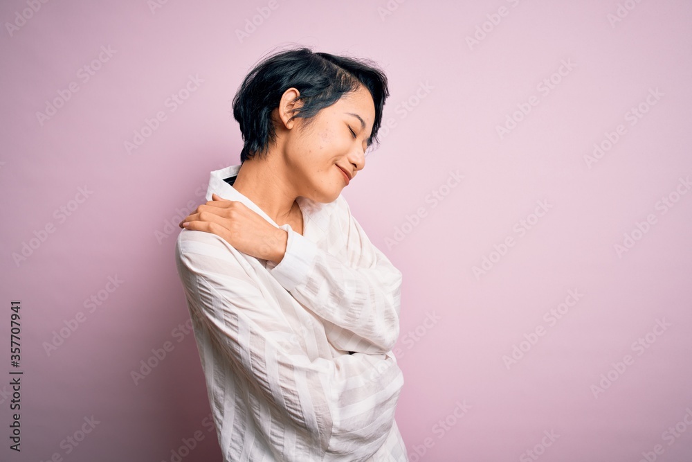 Young beautiful asian girl wearing casual shirt standing over isolated pink background Hugging oneself happy and positive, smiling confident. Self love and self care Young beautiful asian girl wearing casual shirt standing over isolated pink background Hugging oneself happy and positive, smiling confident. Self love and self care