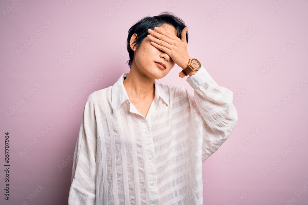 Young beautiful asian girl wearing casual shirt standing over isolated pink background covering eyes with hand, looking serious and sad. Sightless, hiding and rejection concept Young beautiful asian girl wearing casual shirt standing over isolated pink background covering eyes with hand, looking serious and sad. Sightless, hiding and rejection concept