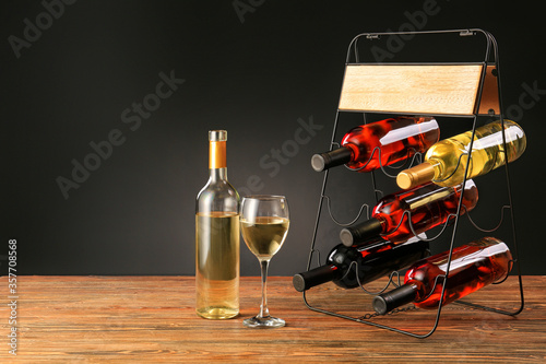 Holder with bottles and glass of wine on table