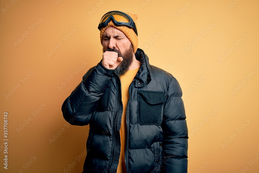 Handsome skier bald man with beard skiing wearing snow sportswear and ski goggles feeling unwell and coughing as symptom for cold or bronchitis. Health care concept. Handsome skier bald man with beard skiing wearing snow sportswear and ski goggles feeling unwell and coughing as symptom for cold or bronchitis. Health care concept.