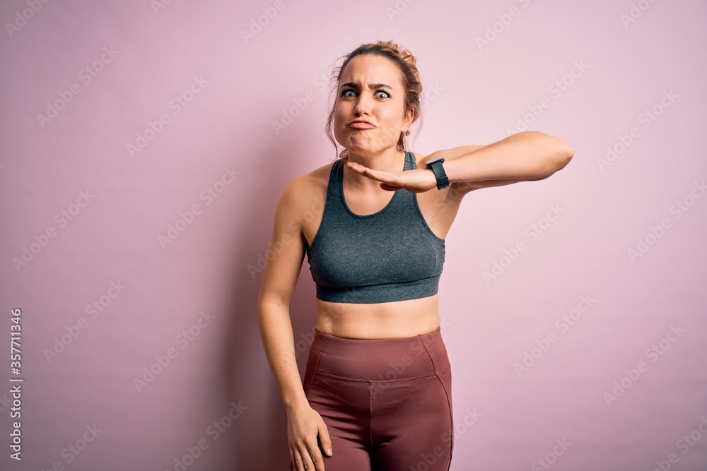 Young beautiful blonde sportswoman doing sport wearing sportswear over pink background cutting throat with hand as knife, threaten aggression with furious violence Young beautiful blonde sportswoman doing sport wearing sportswear over pink background cutting throat with hand as knife, threaten aggression with furious violence