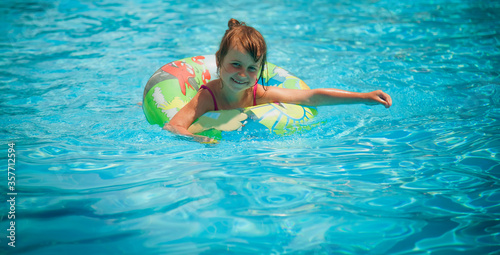Pretty little girl in the outdoor pool. Horizontal image.