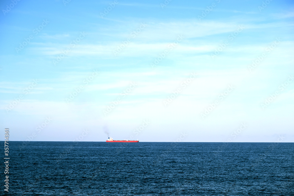 A smoking cargo oil tanker ship on the horizon of blue sea. A smoking cargo oil tanker ship on the horizon of blue sea.