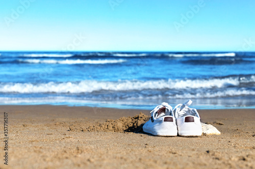 Sneakers on the sand. Alone on the beach. Holiday with coronavirus. © Mike Sagan