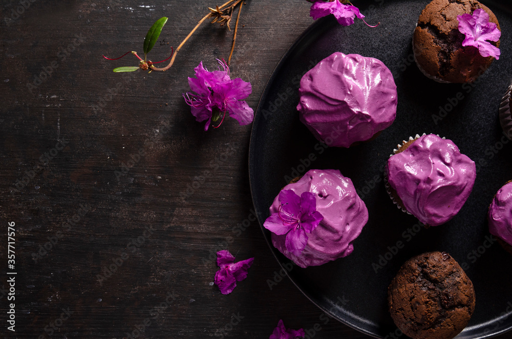 Chocolate cupcakes with beetroot cream on a dark background with flower - labrador tea or rhododendron Chocolate cupcakes with beetroot cream on a dark background with flower - labrador tea or rhododendron