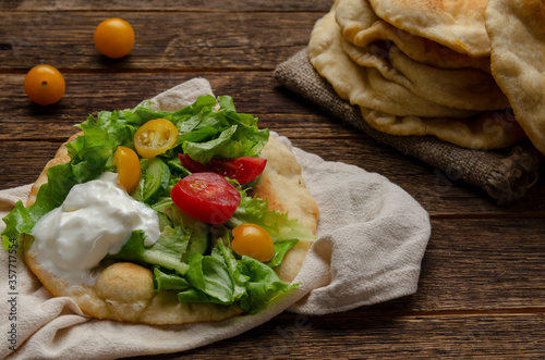 Navajo fried bread with green salad and yougurt on wooden background