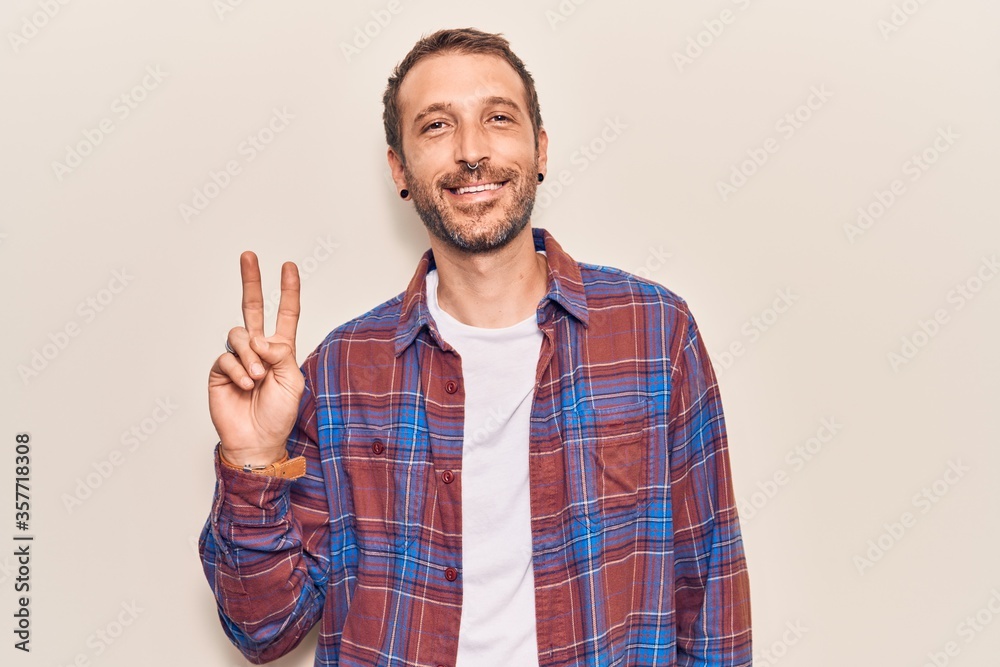Young handsome man wearing casual clothes smiling with happy face winking at the camera doing victory sign. number two. Young handsome man wearing casual clothes smiling with happy face winking at the camera doing victory sign. number two.