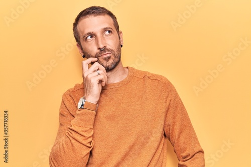 Young handsome man wearing casual clothes serious face thinking about question with hand on chin, thoughtful about confusing idea