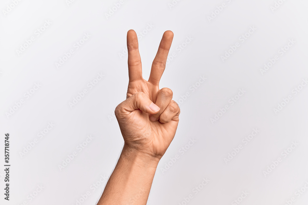 Hand of caucasian young man showing fingers over isolated white background counting number 2 showing two fingers, gesturing victory and winner symbol Hand of caucasian young man showing fingers over isolated white background counting number 2 showing two fingers, gesturing victory and winner symbol