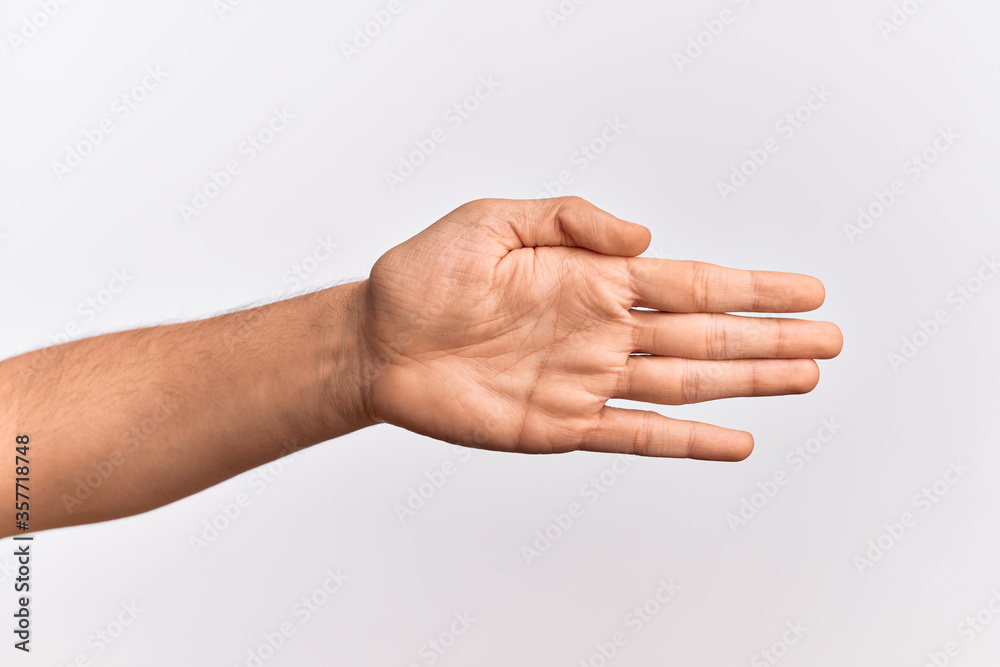Hand of caucasian young man showing fingers over isolated white background stretching and reaching with open hand for handshake, showing palm Hand of caucasian young man showing fingers over isolated white background stretching and reaching with open hand for handshake, showing palm