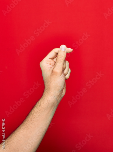 Beautiful hand of man showing fingers raised up doing money sign over isolated red background