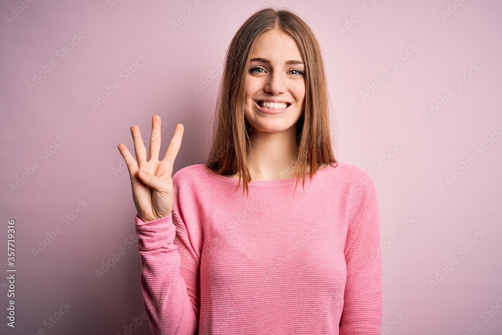 Young beautiful redhead woman wearing casual sweater over isolated pink background showing and pointing up with fingers number four while smiling confident and happy. Young beautiful redhead woman wearing casual sweater over isolated pink background showing and pointing up with fingers number four while smiling confident and happy.