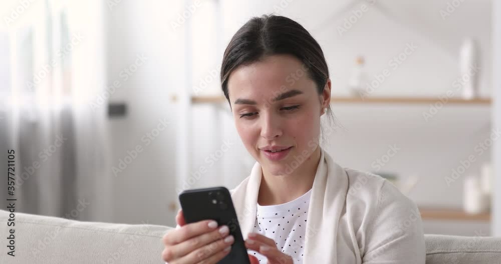 Head shot smiling pretty millennial 20s girl holding smartphone in hands, communicating with friends in social networks online, relaxing alone at home. Happy young woman shopping in internet store. Head shot smiling pretty millennial 20s girl holding smartphone in hands, communicating with friends in social networks online, relaxing alone at home. Happy young woman shopping in internet store.