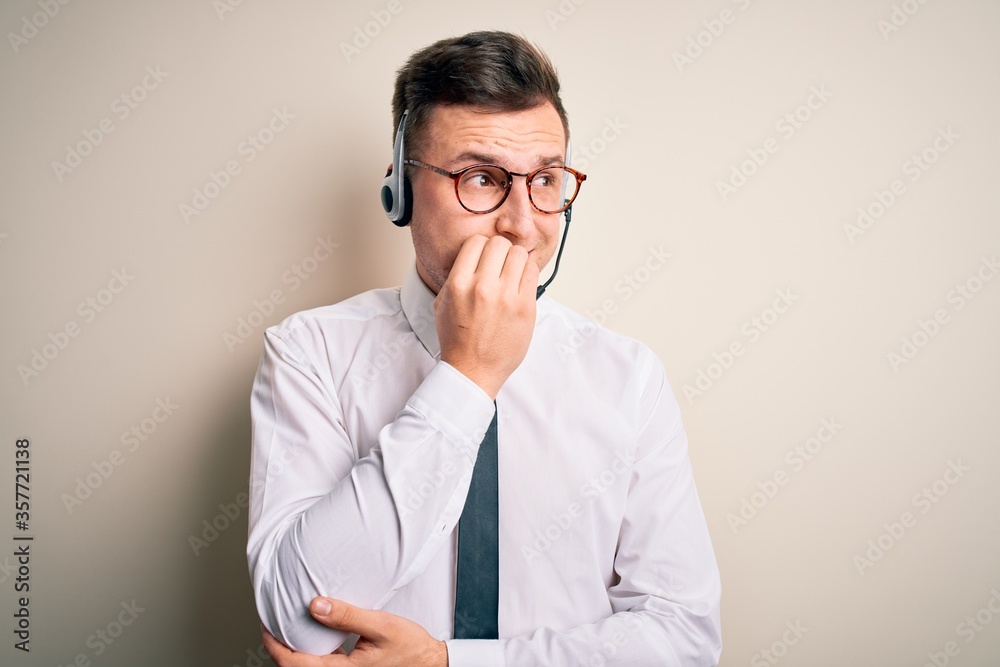Young handsome caucasian business man wearing call center headset at customer service looking stressed and nervous with hands on mouth biting nails. Anxiety problem.