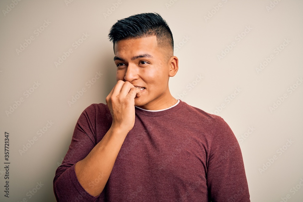 Young handsome latin man wearing casual sweater standing over isolated white background looking stressed and nervous with hands on mouth biting nails. Anxiety problem. Young handsome latin man wearing casual sweater standing over isolated white background looking stressed and nervous with hands on mouth biting nails. Anxiety problem.