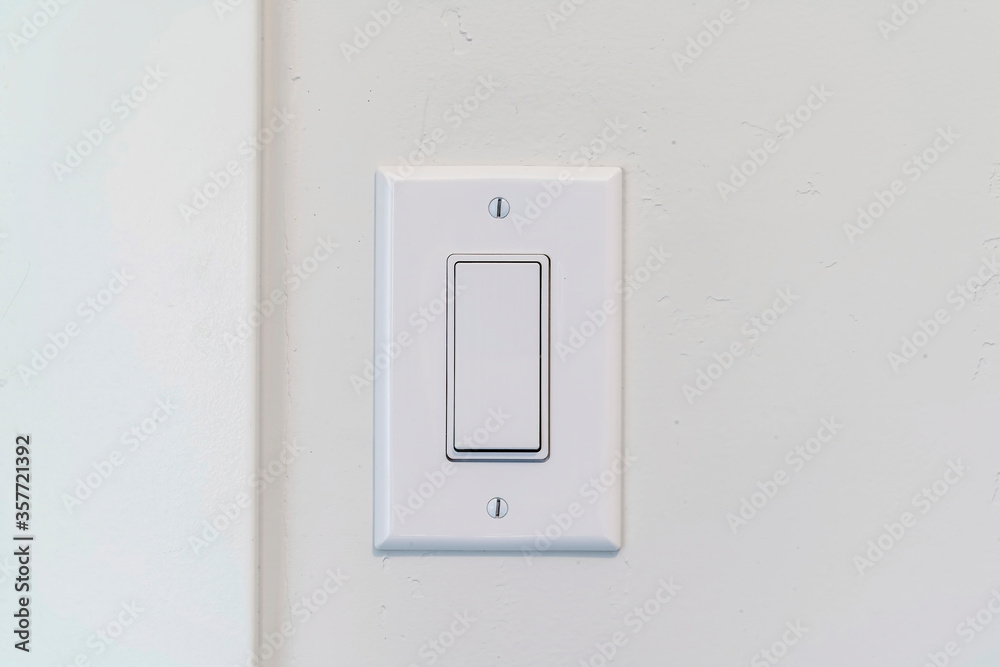 Electrical rocker light switch with flat broad lever on white interior wall Electrical rocker light switch with flat broad lever on white interior wall