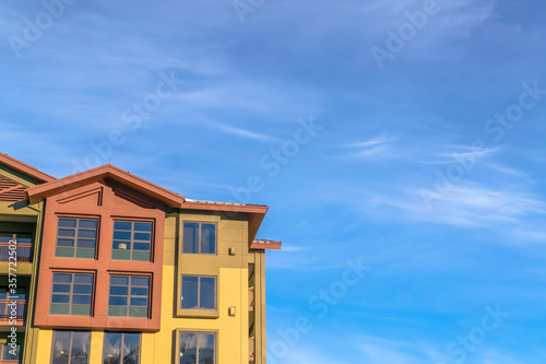 Home exterior with balconies and multi color walls against blue sky and clouds