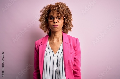 Young african american businesswoman wearing glasses standing over pink background depressed and worry for distress, crying angry and afraid. Sad expression.