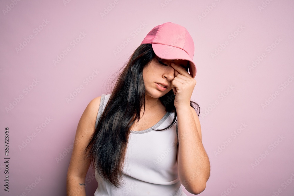 Young brunette woman wearing casual sport cap over pink background tired rubbing nose and eyes feeling fatigue and headache. Stress and frustration concept.