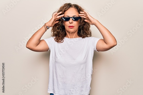 Middle age beautiful woman wearing funny thug life sunglasses over white background with hand on head, headache because stress. Suffering migraine.