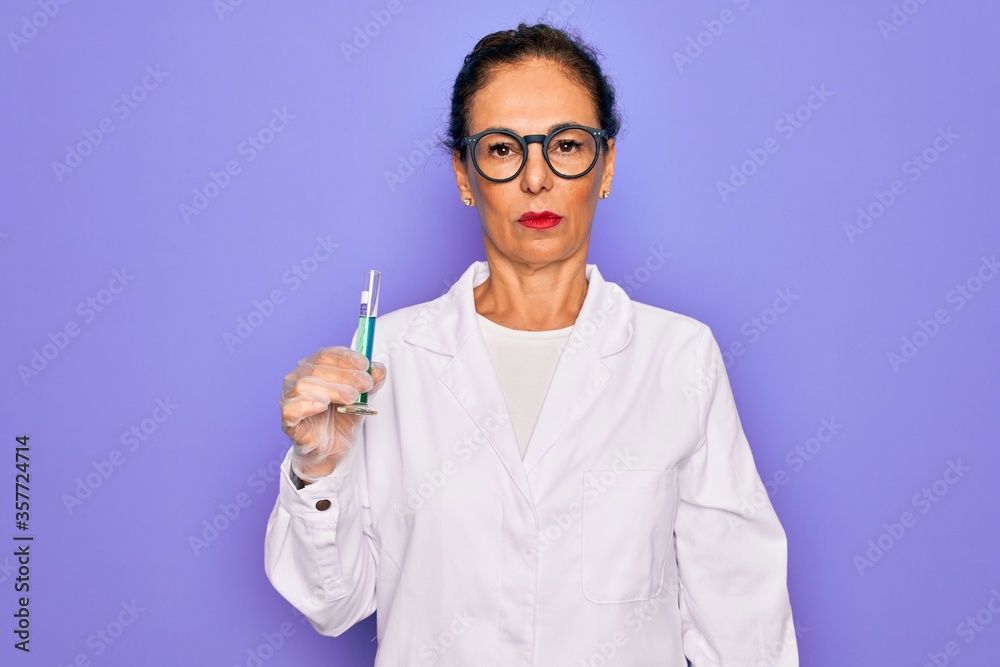 Middle age senior scientist woman wearing laboratory coat holding research test tube with a confident expression on smart face thinking serious Middle age senior scientist woman wearing laboratory coat holding research test tube with a confident expression on smart face thinking serious