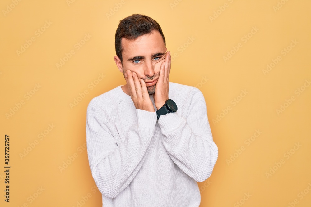 Young handsome man with blue eyes wearing casual sweater standing over yellow background Tired hands covering face, depression and sadness, upset and irritated for problem Young handsome man with blue eyes wearing casual sweater standing over yellow background Tired hands covering face, depression and sadness, upset and irritated for problem