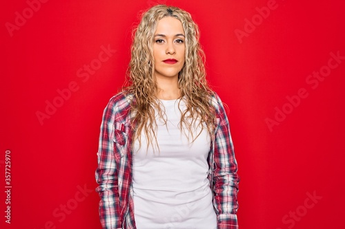 Young beautiful blonde woman wearing casual shirt standing over isolated red background looking sleepy and tired, exhausted for fatigue and hangover, lazy eyes in the morning.
