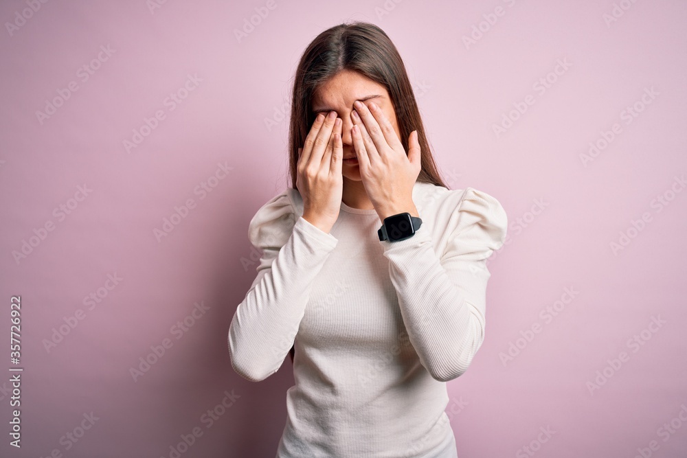 Young beautiful woman with blue eyes wearing casual white t-shirt over pink background rubbing eyes for fatigue and headache, sleepy and tired expression. Vision problem Young beautiful woman with blue eyes wearing casual white t-shirt over pink background rubbing eyes for fatigue and headache, sleepy and tired expression. Vision problem