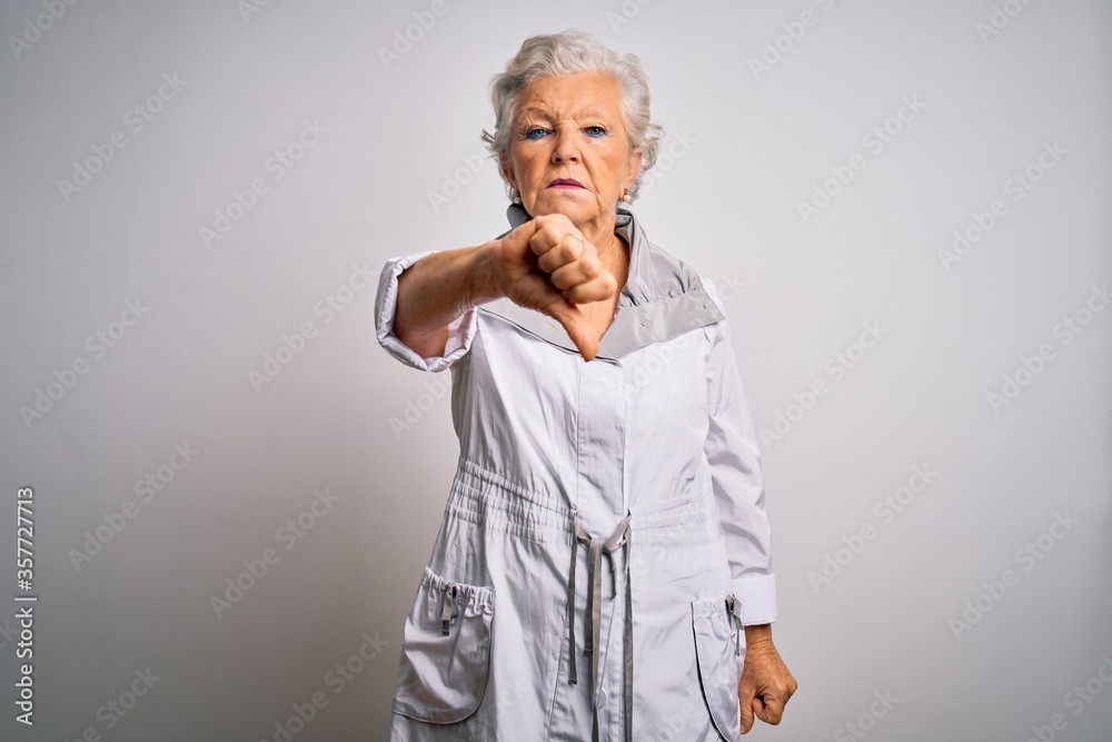Senior beautiful grey-haired woman wearing casual jacket standing over white background looking unhappy and angry showing rejection and negative with thumbs down gesture. Bad expression.