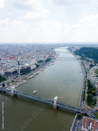 Aerial view of Danube river in Budapest city. Hungary Europe. Bridges, river bifurcates. Summer. Blue sky. Nature. Water transport, boats and ferries moored near riverside.
 photo